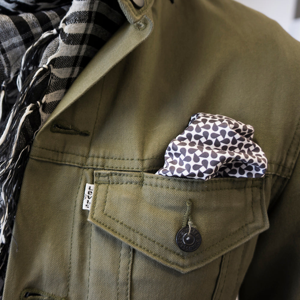 Green jacket with a keffiyeh patterned black and white pocket square.