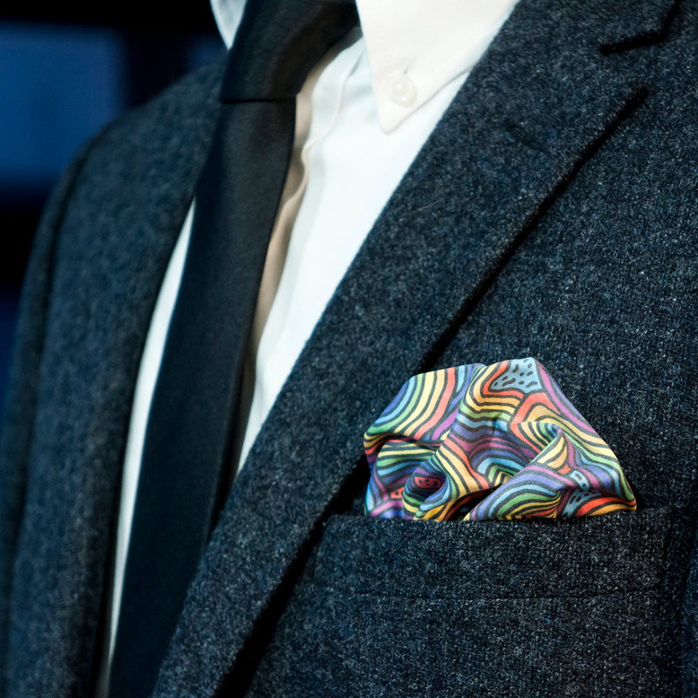 Dark gray suit with a colorful rainbow patterned pocket square.