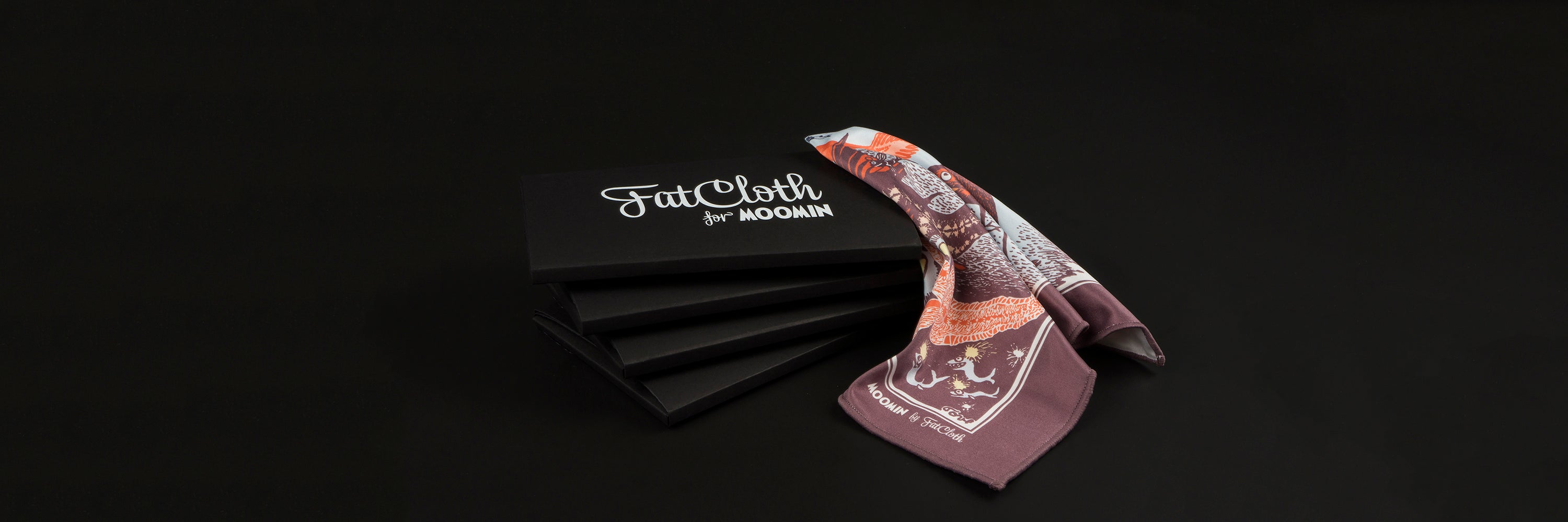 A set of black FatCloth boxes with a maroon pocket square on black background