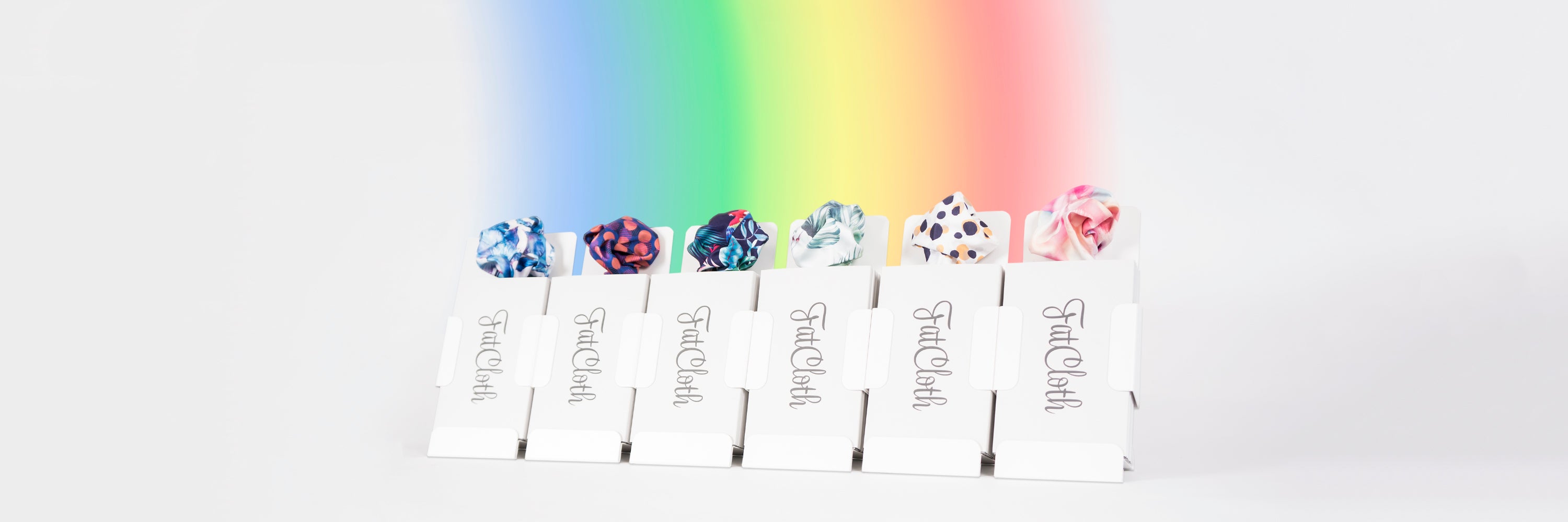 Six FatCloth product displays in row with a rainbow rising behind them
