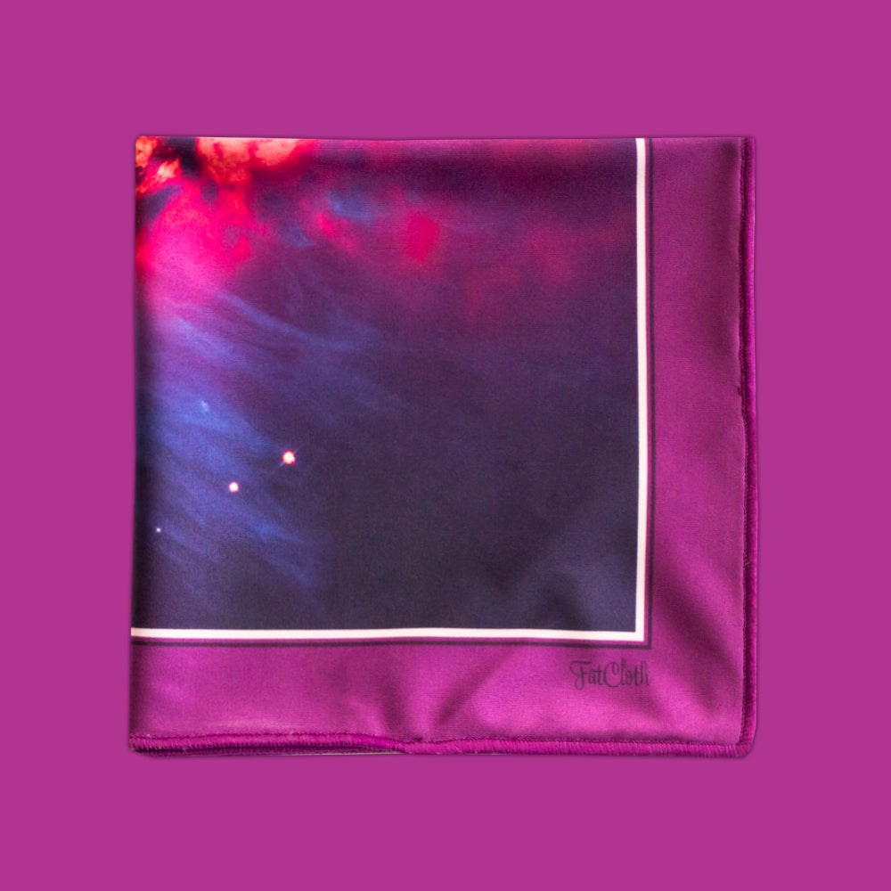 A multipurpose pocket square with a cosmic nebula print in purple, blue, and red, framed by a magenta border and featuring the FatCloth logo.